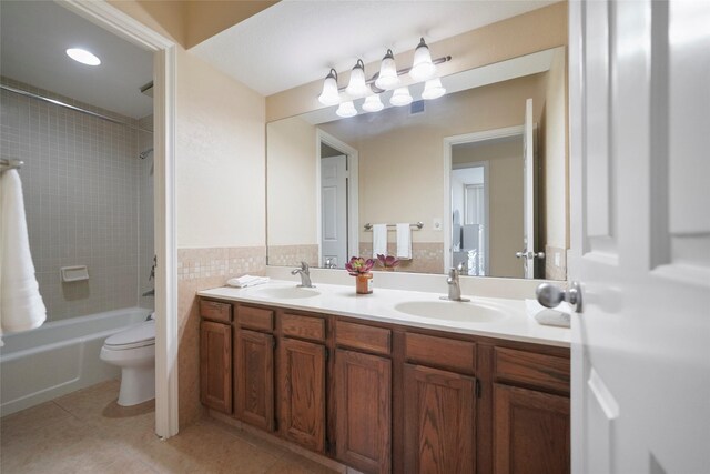 full bath with tile patterned flooring, double vanity, toilet, bathtub / shower combination, and tile walls