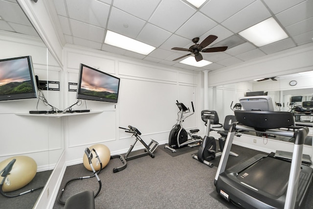 exercise room with ceiling fan, a drop ceiling, and carpet
