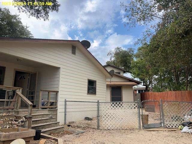 view of side of home featuring fence and a gate