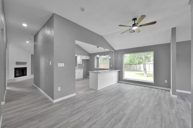 22603 Pebworth Pl, Spring, TX 77373 - unfurnished living room with ceiling fan, light wood finished floors, a fireplace, vaulted ceiling, and baseboards