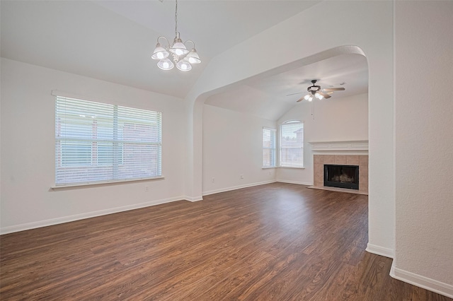 unfurnished living room with a tile fireplace, ceiling fan with notable chandelier, dark wood-type flooring, baseboards, and lofted ceiling