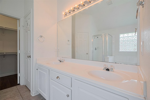 full bathroom featuring a sink, double vanity, a shower stall, and visible vents