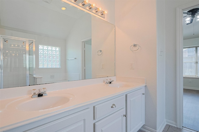bathroom featuring double vanity, a stall shower, ceiling fan, and a sink