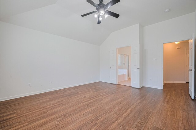 unfurnished bedroom featuring wood finished floors, a ceiling fan, baseboards, ensuite bath, and lofted ceiling