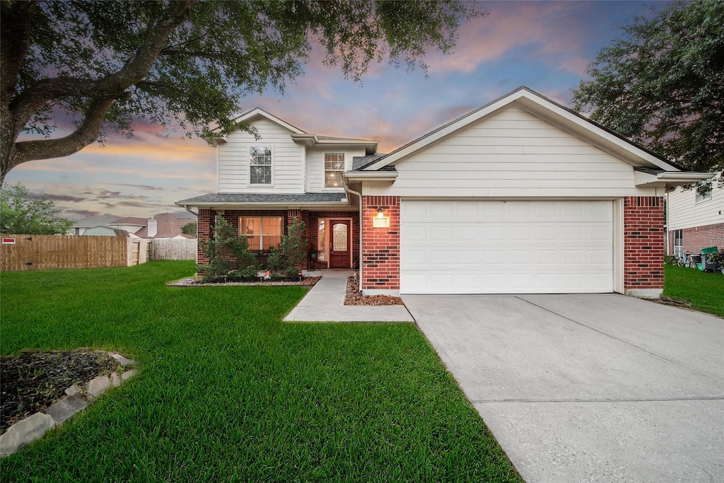 traditional-style home with driveway, brick siding, fence, an attached garage, and a front lawn