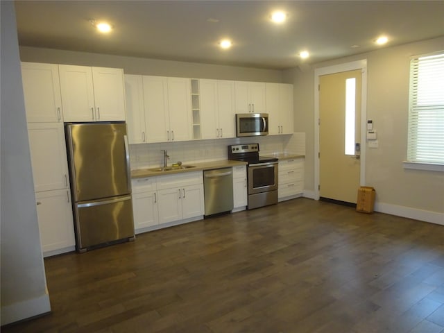 2401 Crawford Unit 105, Houston, TX 77004 - kitchen featuring stainless steel appliances, a sink, baseboards, backsplash, and white cabinetry