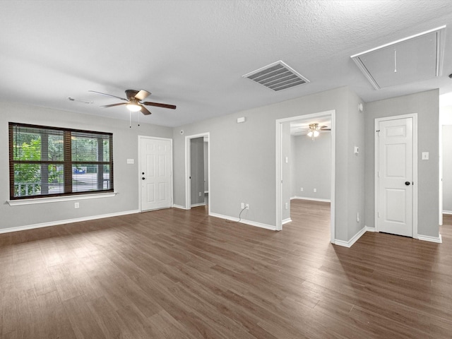 unfurnished living room with attic access, visible vents, ceiling fan, dark wood-style floors, and baseboards