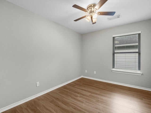 spare room with baseboards, visible vents, wood finished floors, and a ceiling fan