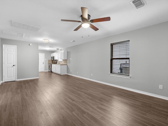 unfurnished living room with a ceiling fan, attic access, visible vents, and dark wood-style floors