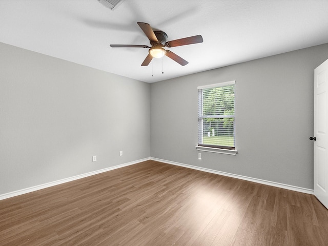 empty room featuring a ceiling fan, baseboards, and wood finished floors