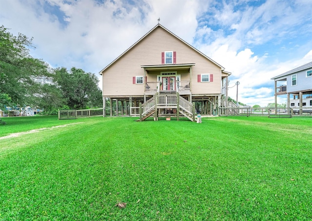 rear view of property with stairs, fence, and a lawn