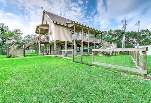 back of property with roof with shingles, fence, a lawn, and stairs