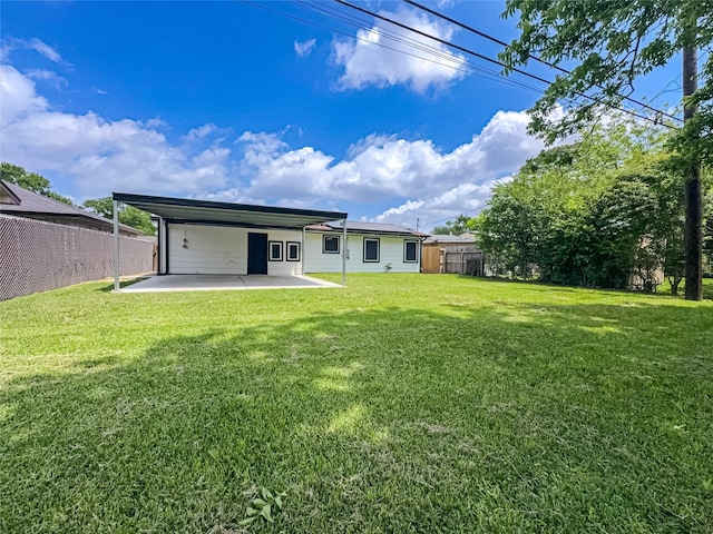 rear view of house featuring a patio area, a carport, fence, and a lawn
