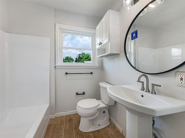 bathroom with toilet, wood finished floors, baseboards, and a sink