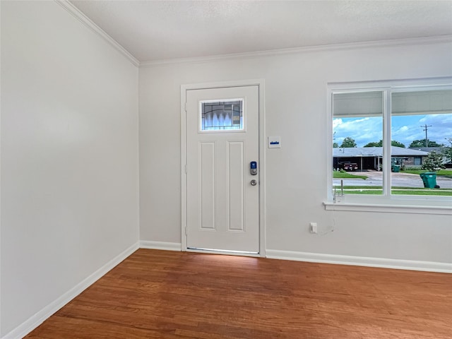 foyer with wood finished floors, baseboards, and ornamental molding