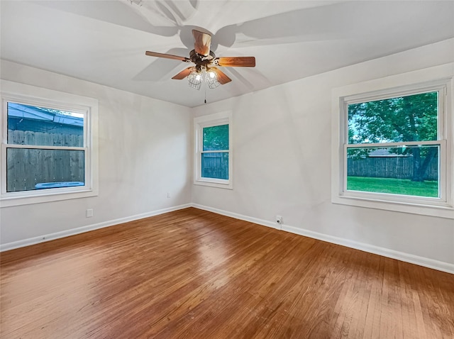 unfurnished room with wood finished floors, baseboards, and a ceiling fan