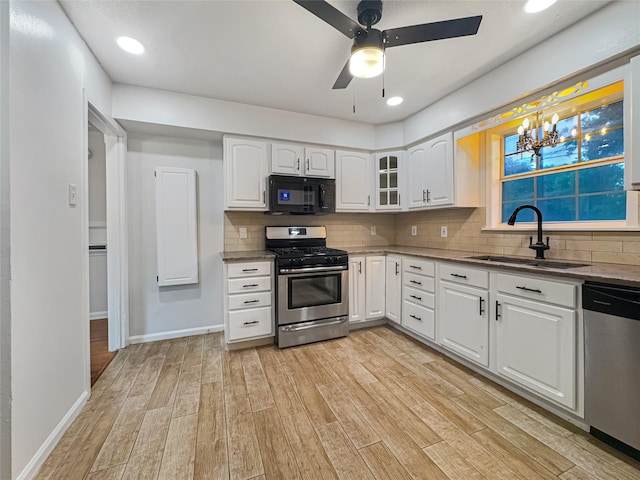 kitchen with a sink, backsplash, light wood-style floors, stainless steel appliances, and white cabinets