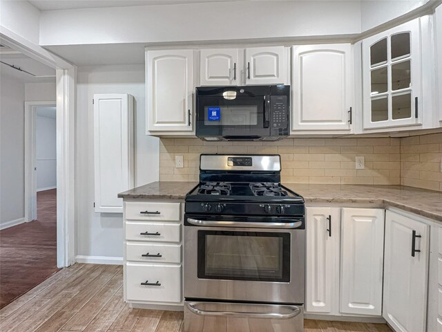 kitchen featuring light stone countertops, light wood finished floors, white cabinetry, gas range, and black microwave