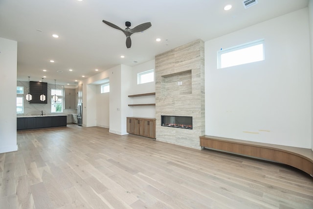 4709 Gibson St, Houston, TX 77007 - unfurnished living room featuring a ceiling fan, recessed lighting, a tile fireplace, and light wood-style floors