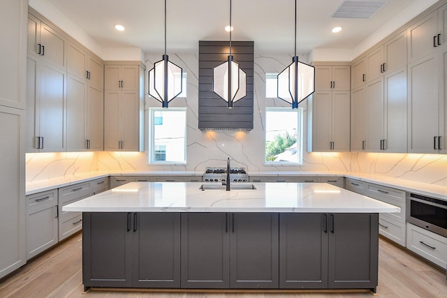 4709 Gibson St, Houston, TX 77007 - kitchen with gray cabinets, tasteful backsplash, light wood-type flooring, light stone counters, and recessed lighting