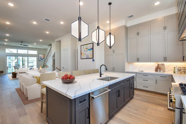 4709 Gibson St, Houston, TX 77007 - kitchen featuring stainless steel dishwasher, gray cabinets, ceiling fan, an island with sink, and light wood-style floors