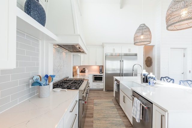 201 Lakeshore St, Port Aransas, TX 78373 - kitchen with premium appliances, light wood finished floors, white cabinetry, decorative backsplash, and a high ceiling