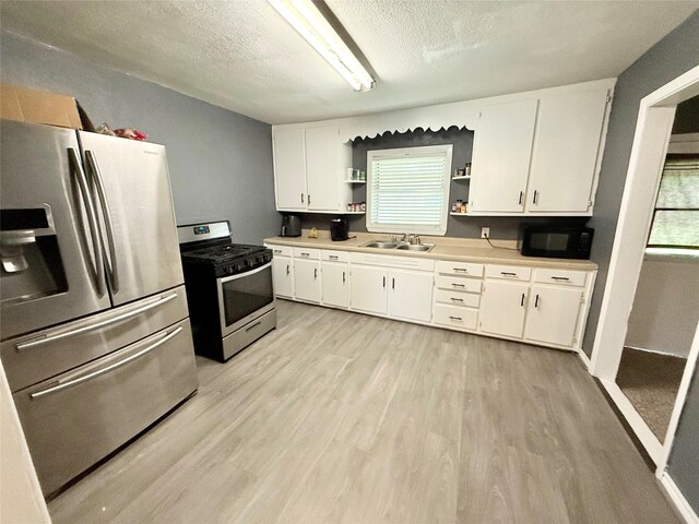 231 Moore St, Richwood, TX 77531 - kitchen with light wood-style flooring, a textured ceiling, a sink, open shelves, and stainless steel appliances