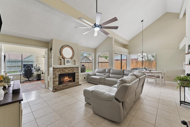 living room featuring light tile patterned floors, ceiling fan with notable chandelier, a stone fireplace, and high vaulted ceiling