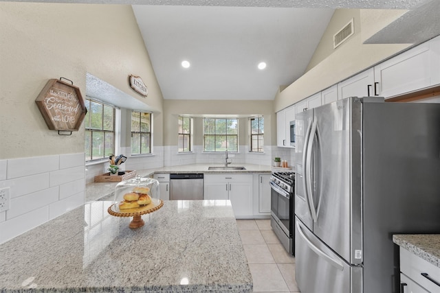 kitchen featuring light stone counters, visible vents, a sink, white cabinetry, and stainless steel appliances