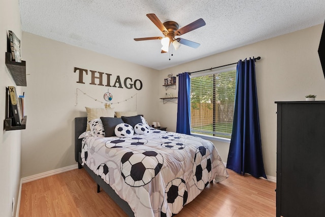 bedroom featuring light wood finished floors, a textured ceiling, baseboards, and ceiling fan