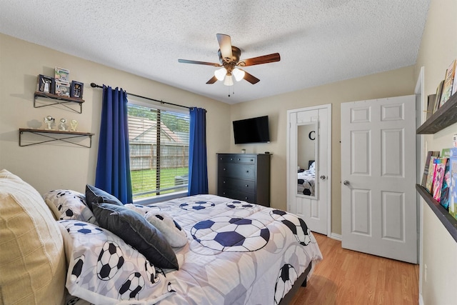 bedroom featuring ceiling fan, a textured ceiling, and light wood-type flooring