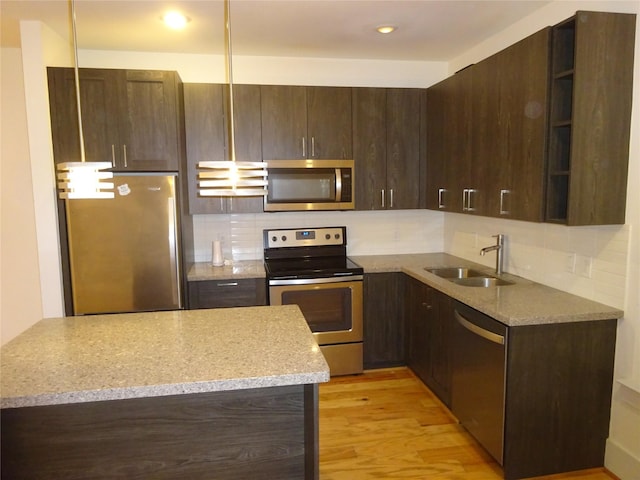kitchen with open shelves, appliances with stainless steel finishes, a sink, and dark brown cabinetry