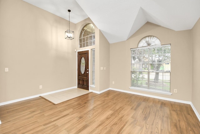 foyer featuring vaulted ceiling, light wood-style floors, a chandelier, and baseboards