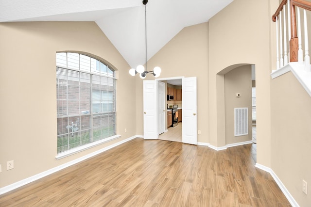 unfurnished dining area with high vaulted ceiling, visible vents, arched walkways, baseboards, and light wood-style floors