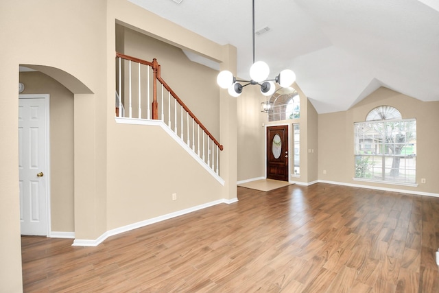 foyer entrance featuring arched walkways, stairway, an inviting chandelier, and wood finished floors