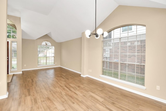 interior space with lofted ceiling, baseboards, an inviting chandelier, and wood finished floors