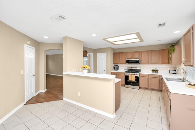 kitchen with visible vents, a sink, arched walkways, light countertops, and appliances with stainless steel finishes