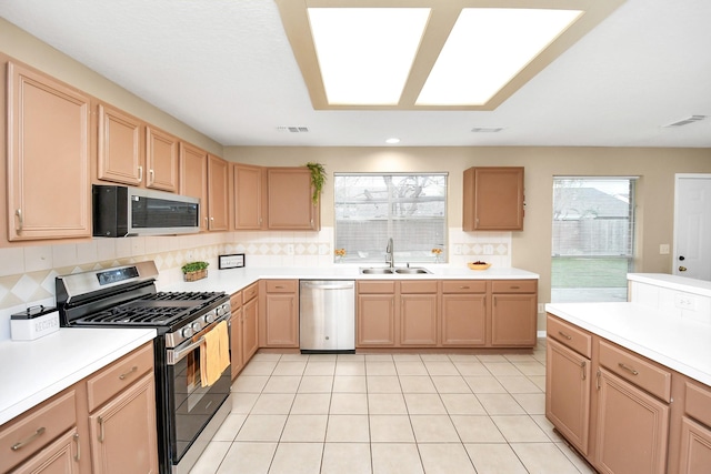 kitchen with a sink, stainless steel appliances, light brown cabinets, and visible vents