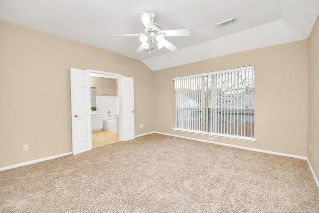 unfurnished bedroom featuring baseboards, carpet flooring, ensuite bath, and lofted ceiling