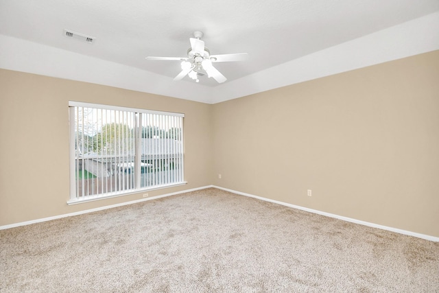 carpeted empty room with baseboards, a ceiling fan, and visible vents