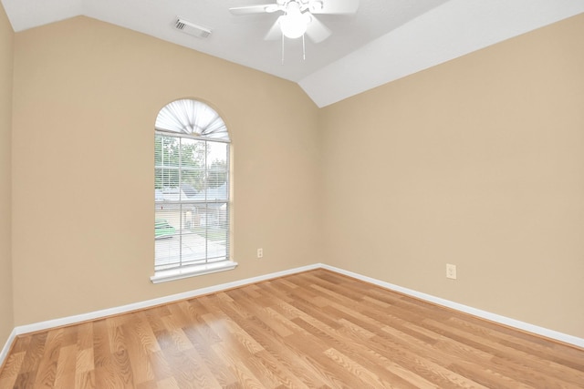 spare room with lofted ceiling, light wood-type flooring, visible vents, and a ceiling fan