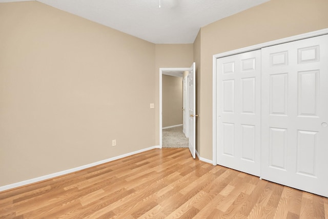unfurnished bedroom featuring a closet, light wood-style floors, baseboards, and ceiling fan