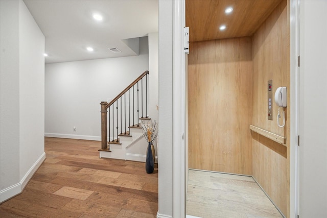 hall featuring elevator, wood finished floors, recessed lighting, and stairway