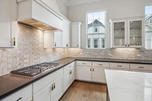3606 Lannister Ln, Houston, TX 77055 - kitchen featuring stainless steel gas stovetop, premium range hood, white cabinetry, dark stone counters, and tasteful backsplash