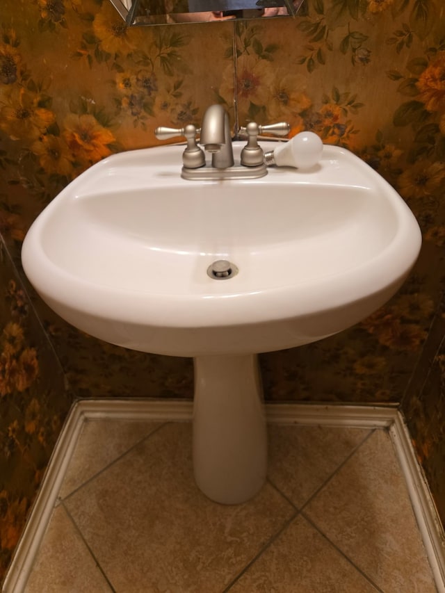 bathroom featuring tile patterned floors, baseboards, wallpapered walls, and a sink