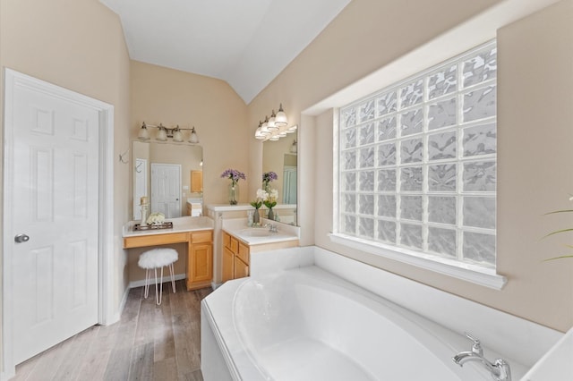 full bath with vanity, lofted ceiling, a bath, and wood finished floors