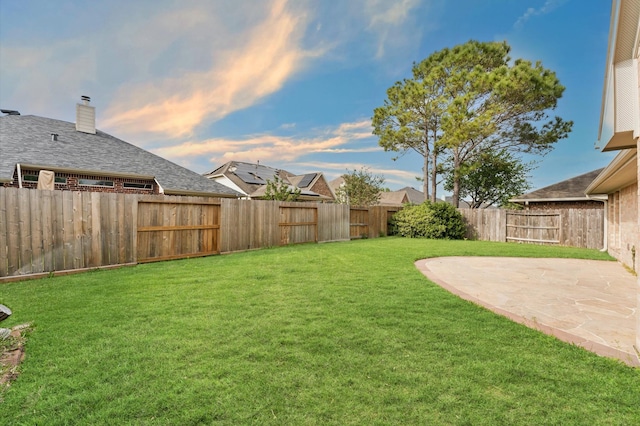 yard at dusk with a patio area and a fenced backyard