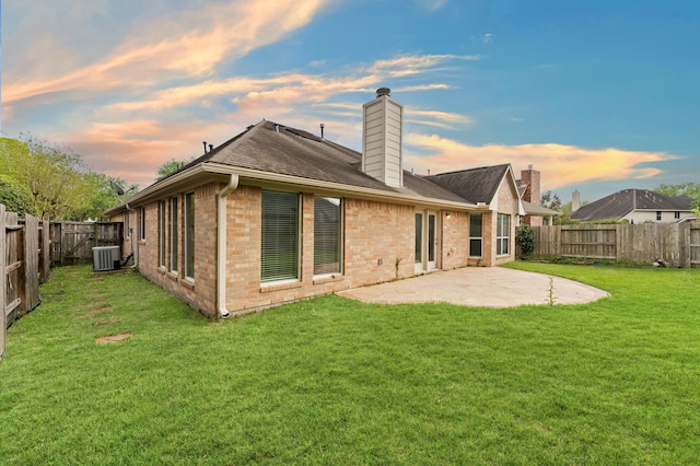 rear view of house featuring a chimney, a patio area, brick siding, and a fenced backyard