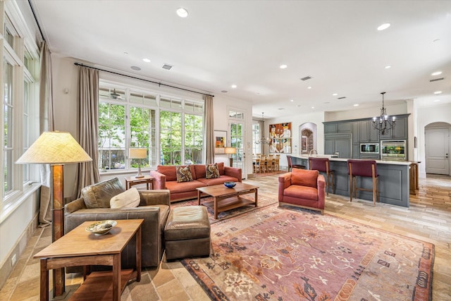 living room featuring an inviting chandelier, arched walkways, plenty of natural light, and recessed lighting