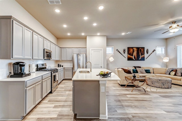 5110 Morrison Dr, Manvel, TX 77578 - kitchen with stainless steel appliances, open floor plan, a sink, a ceiling fan, and light wood-style floors
